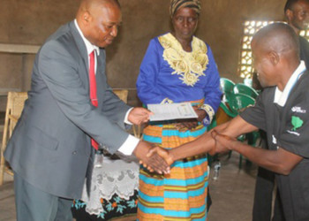 A farmer (R) receives his 
certificate from a trainer