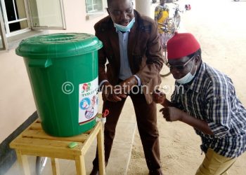 Kawinga (L) washes hands with soap as his colleague looks on