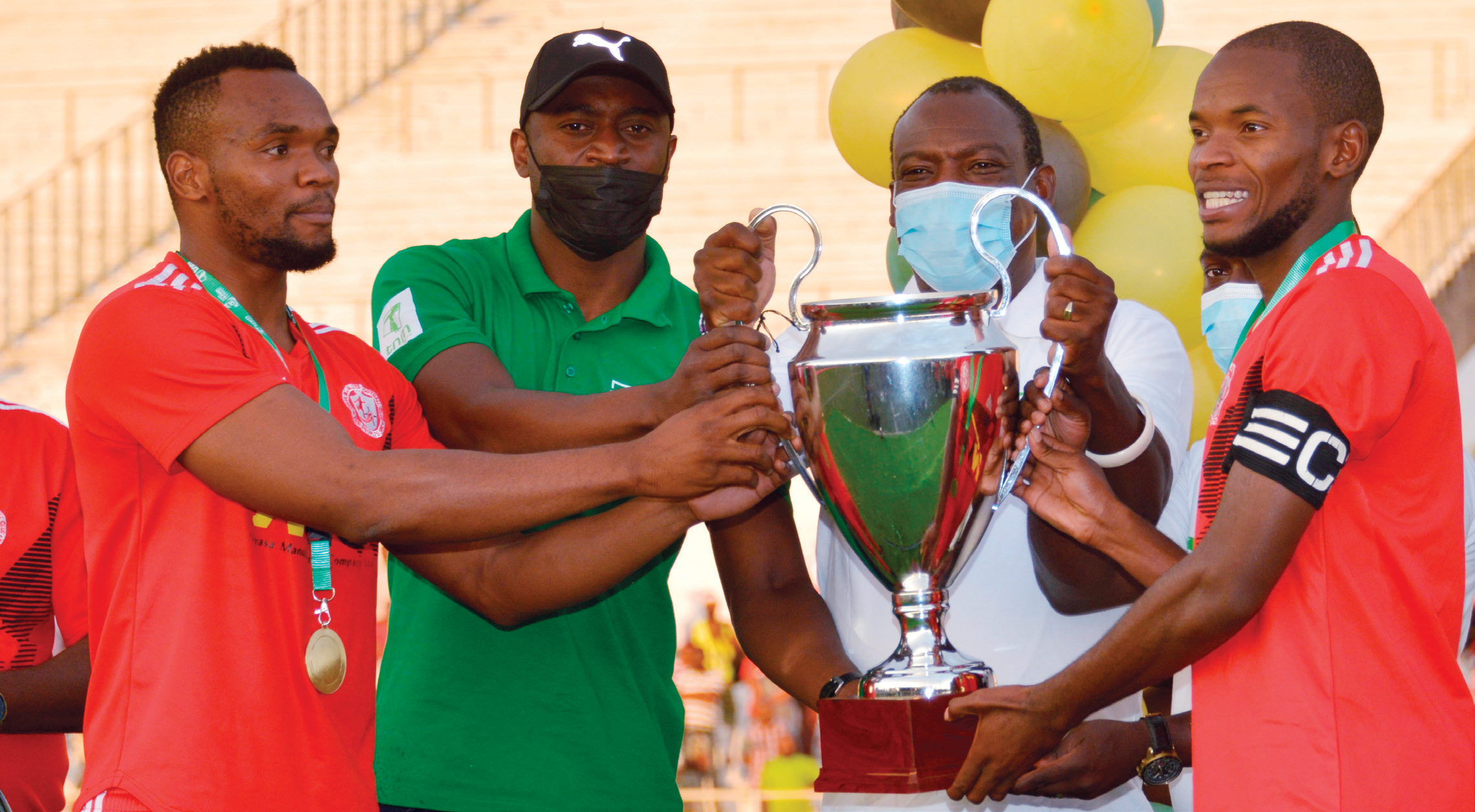 Bullets’ John Lanjesi (L) and Idana (R) receive the trophy from TNM plc’s Madalitso Jonazi (2ndL) and
Malawi National Council of Sports board chairperson Sunduzwayo Madise