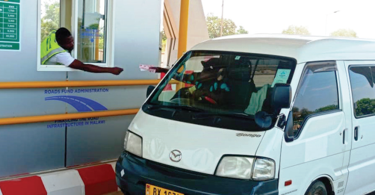 A minibus driver pays toll fees at Chingeni Toll Plaza