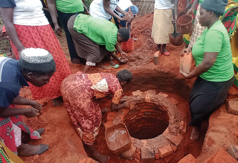 Choma women building a corbelled pit latrine