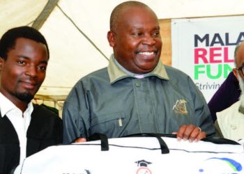 Valli (R) and Chiradzulu district commissioner Francis Matewere (C) hand over a toolkit to a student